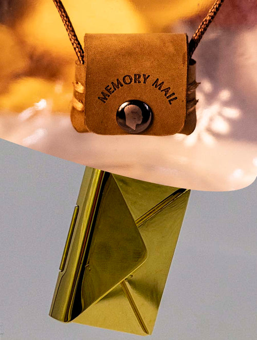 Brown leather pouch necklace with 'Memory Mail' branding on a light gray background with gold stainless steel envelope that can be engraved