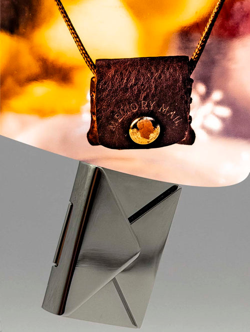 Brown leather pouch with gold clasp on a stand against a blurred background and a stainless steel colored engravable envelope. 